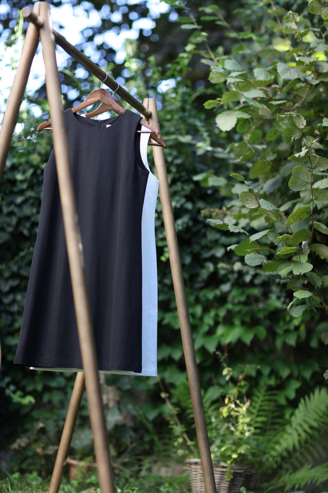 Black and white dress made from natural materials hanging in front of a green tree